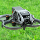 The DJI Avata drone hovering over grass.